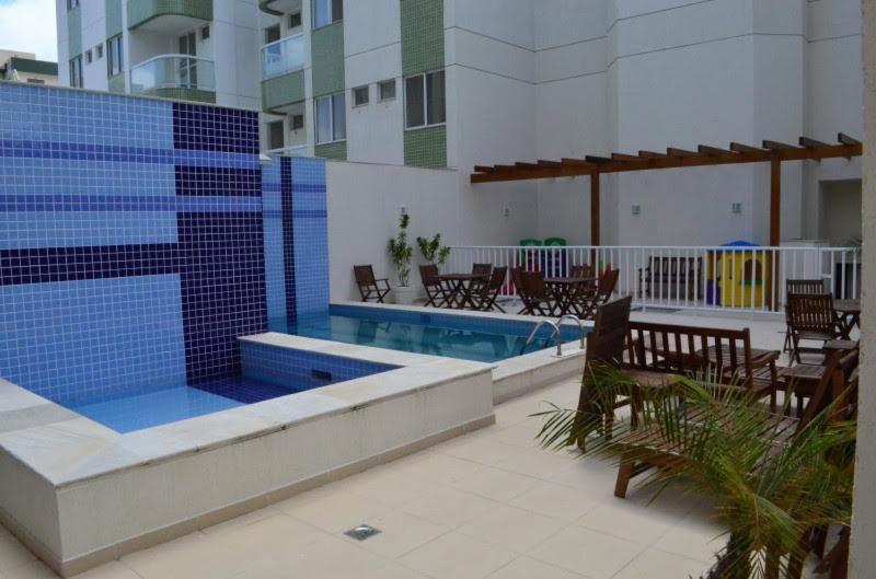 a swimming pool with tables and chairs next to a building at Apto em Cabo Frio com conforto e qualidade. in Cabo Frio