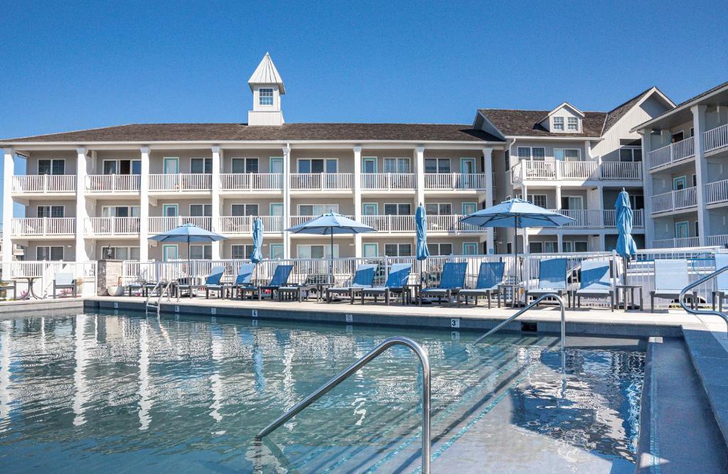 a resort with a pool and chairs and umbrellas at Sandpiper Beach Club in Cape May