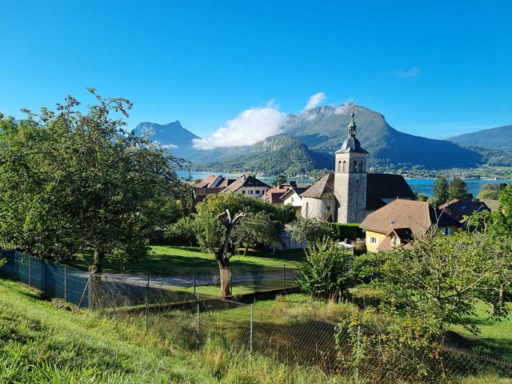 un village avec une église et des montagnes en arrière-plan dans l'établissement Talloires Village, Lac d'Annecy, Résidence récente 4 étoiles, à Talloires