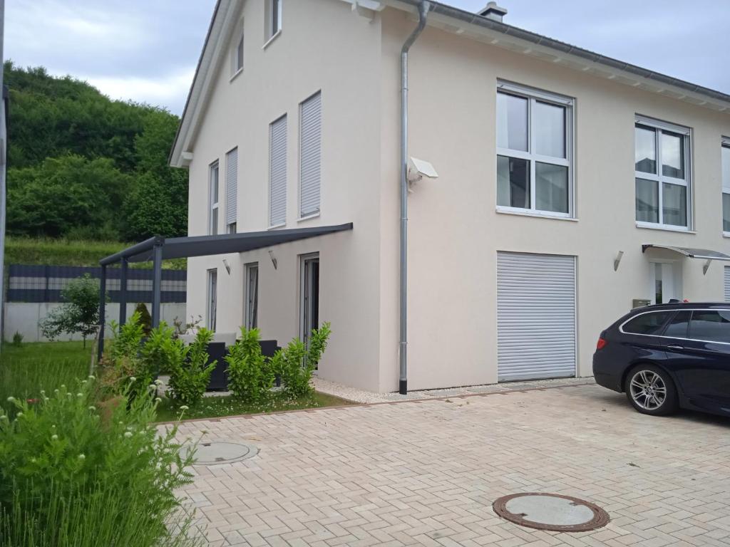 a white house with a car parked in front of it at Ferienwohnung Kleb in Malterdingen