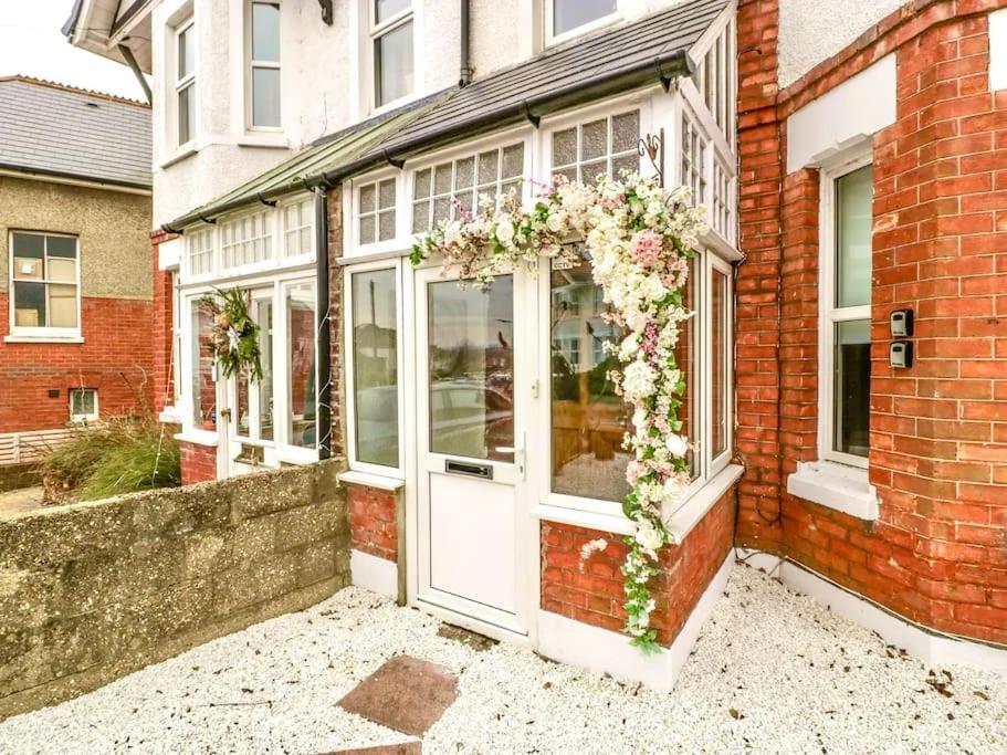 a building with a white door with flowers on it at Homely 4 Bedroom large house inc FREE Parking - Great Location - Fast WiFi - Smart TV - sleeps up to 7! Close to Bournemouth & Poole Town Centre & Sandbanks in Bournemouth