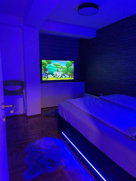 um quarto com uma cama e uma televisão com luzes roxas em Apartman city center 3-šetalište em Prijedor