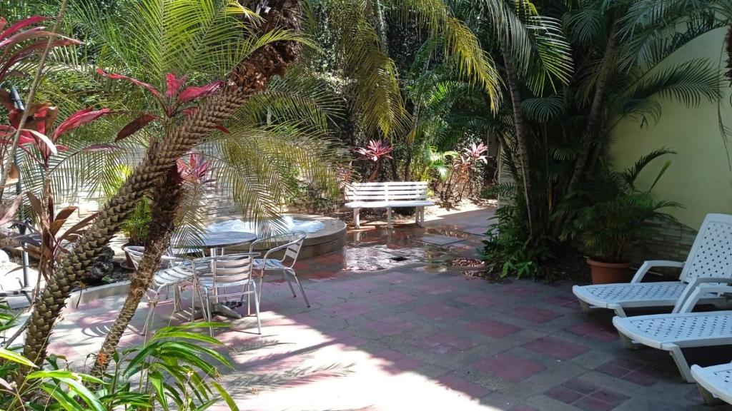un patio con mesa, sillas y palmeras en Apartamento en Guayaquil, sector Urdesa Central, en Guayaquil