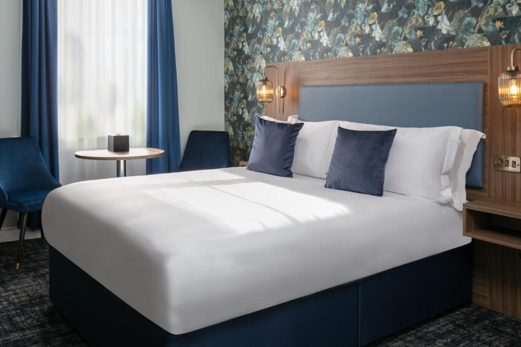 um quarto com uma grande cama branca com almofadas azuis em Best Western Hotel 99 em Blackburn