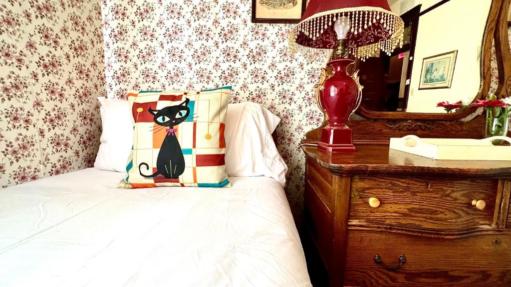 Schlafzimmer mit einem Bett mit Katzenkissen und einem Spiegel in der Unterkunft Hotel La More at The Bisbee Inn in Bisbee