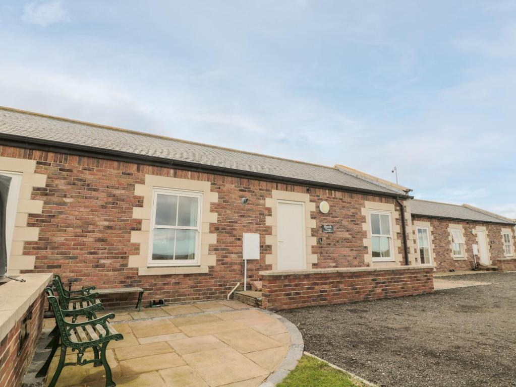 a brick building with a patio and two benches at Bank Top Cottage in Embleton