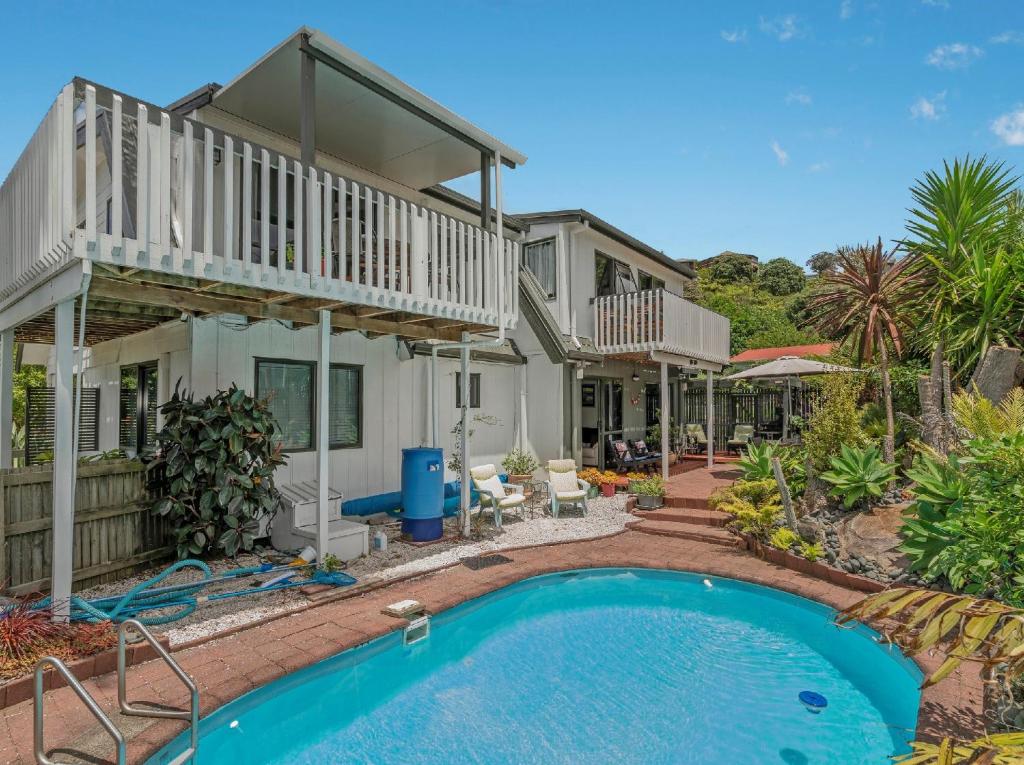 a house with a swimming pool in front of a house at The Harbour View Tairua in Tairua