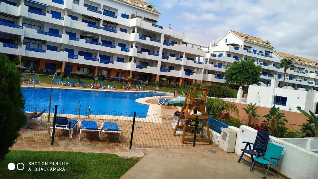 a large apartment building with a large swimming pool at Residencial La Duquesa Suites Golf & Gardens in San Luis de Sabinillas