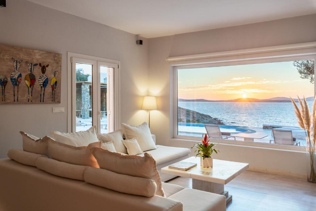 a living room with a couch and a large window at Villa Deloxenia by Ethos Hospitality in Mikonos