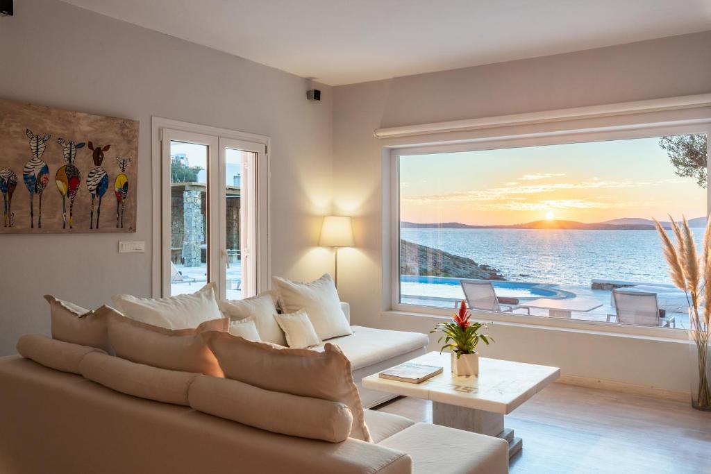 un soggiorno con un divano e una grande finestra di Villa Deloxenia by Ethos Hospitality a Mykonos Città