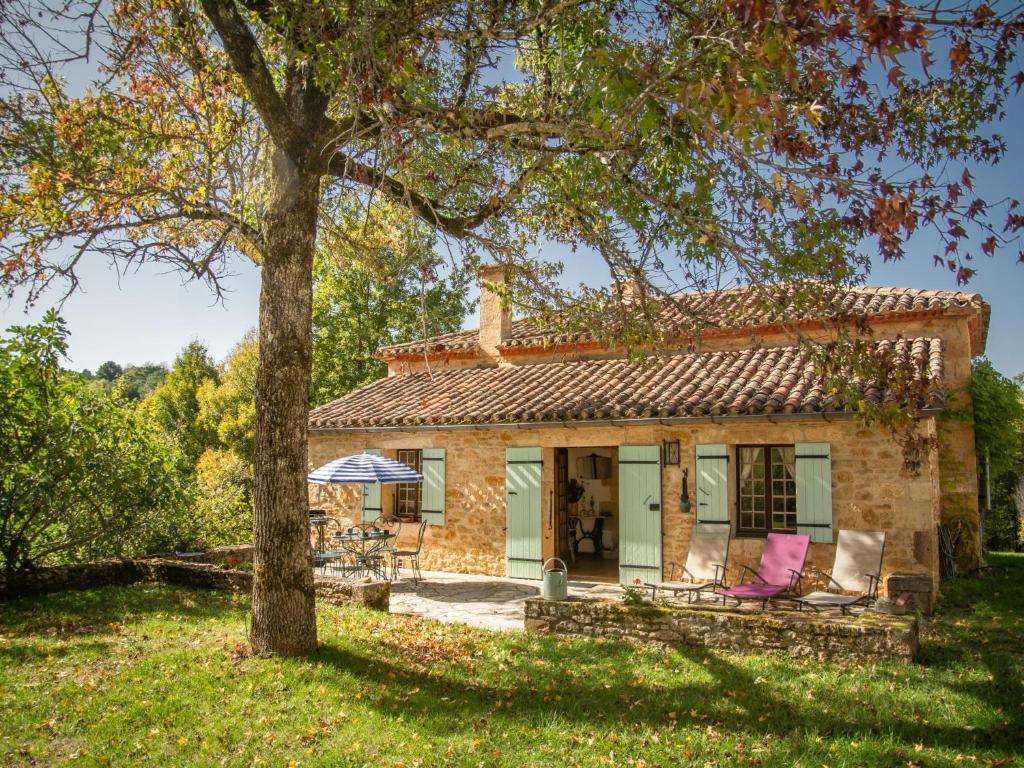 una casa in pietra con sedie rosa e un albero di Maison Sauveterre-la-Lémance a Lapèze