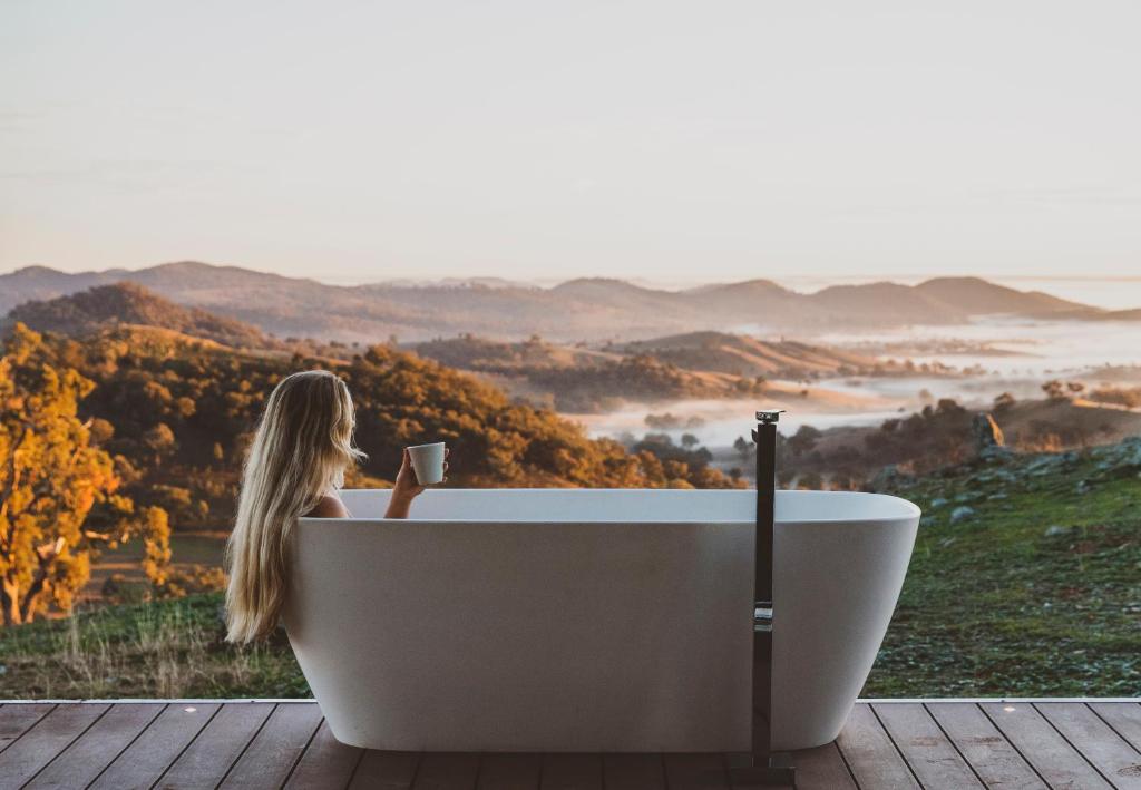 a woman sitting in a bath tub with a cup of coffee at Sierra Escape Luxury Glamping in Piambong