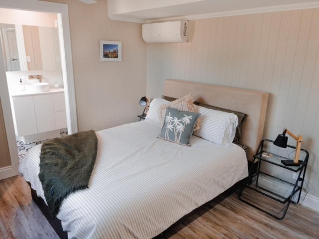 a bedroom with a white bed with pillows and a sink at Coorparoo Comfort Apartment in Brisbane
