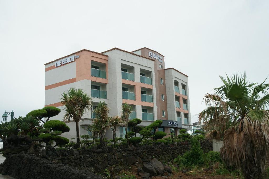 un bâtiment avec des palmiers en face de celui-ci dans l'établissement The Beach Pension, à Jeju