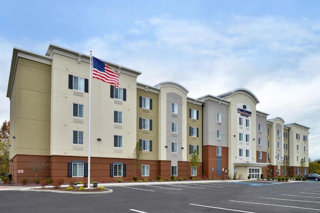 um edifício de apartamentos com uma bandeira americana num parque de estacionamento em Candlewood Suites Sayre, an IHG Hotel em Sayre