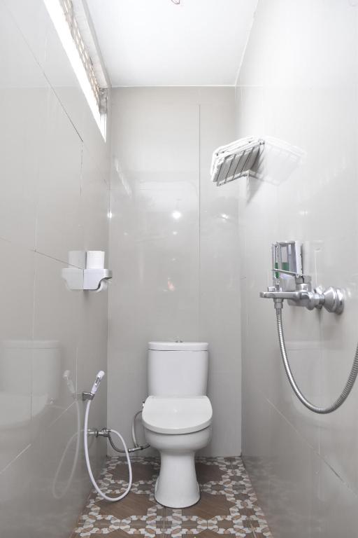 a white bathroom with a toilet and a shower at Grand Malaka Ethical Hotel in Palembang