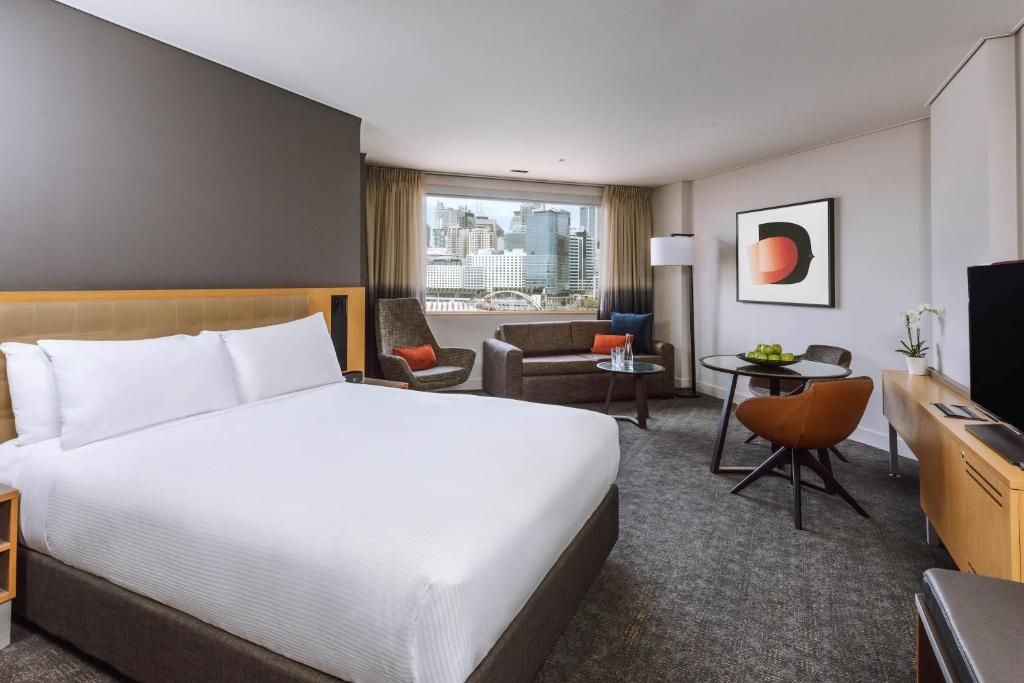 a hotel room with a bed and a living room at Novotel Sydney Darling Harbour in Sydney
