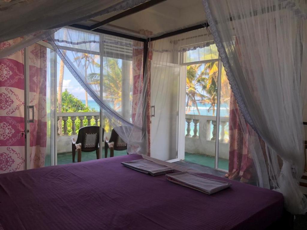una camera con un letto viola e una grande finestra di SunRay Rest - Beach View Homestay a Mirissa