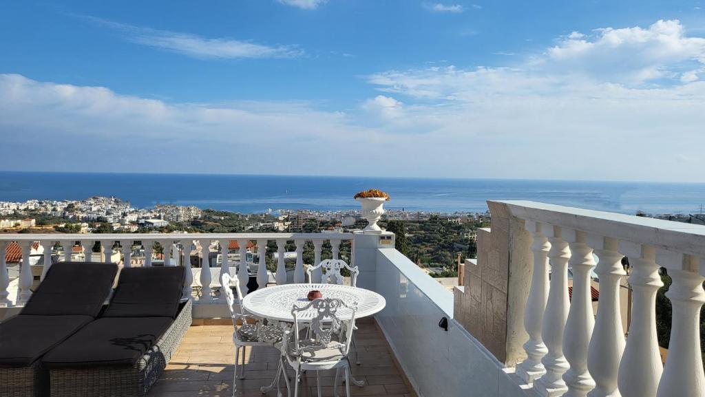 uma varanda com uma mesa e cadeiras e o oceano em Room in Apartment - Beautiful and Spacious Room near Cretan Sea em Hersonissos