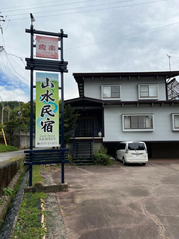 un cartel en un estacionamiento frente a un edificio en 山水民宿, en Takayama