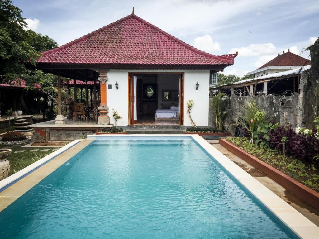 a villa with a swimming pool in front of a house at Escotel Villa Marga in Tabanan