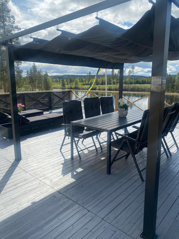 una terraza de madera con mesa y sillas en un barco en Tallbacken Fritidsby en Brännan