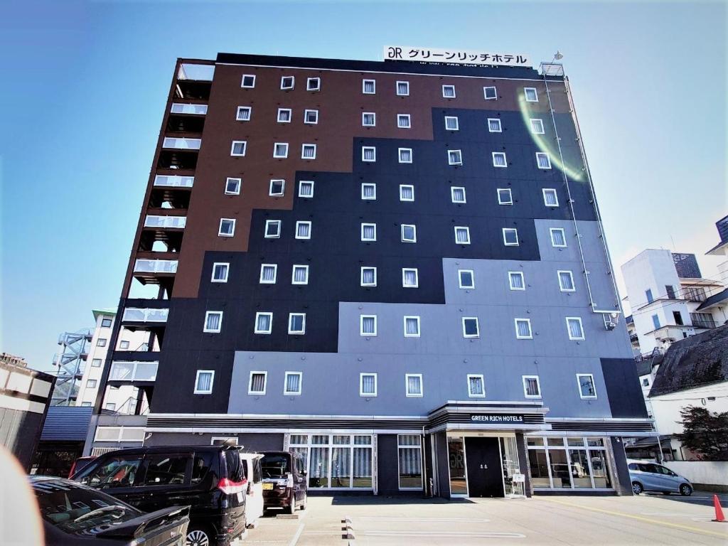 a tall building with cars parked in front of it at Green Rich Hotel Yamaguchi Yuda Onsen in Yamaguchi