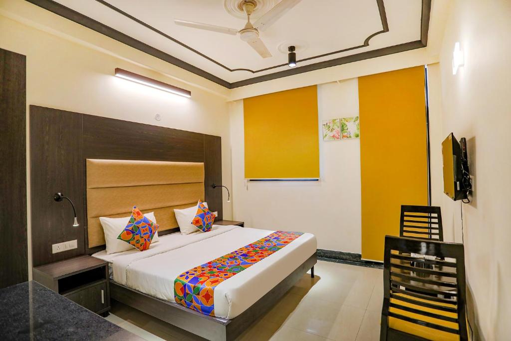 a bedroom with a large bed and a chair at FabHotel NV in Gurgaon