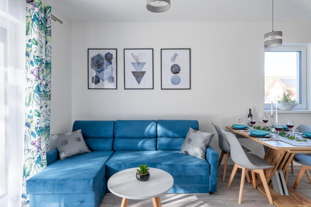a living room with a blue couch and a table at Apartamenty Pod Cisem Lux in Kudowa-Zdrój