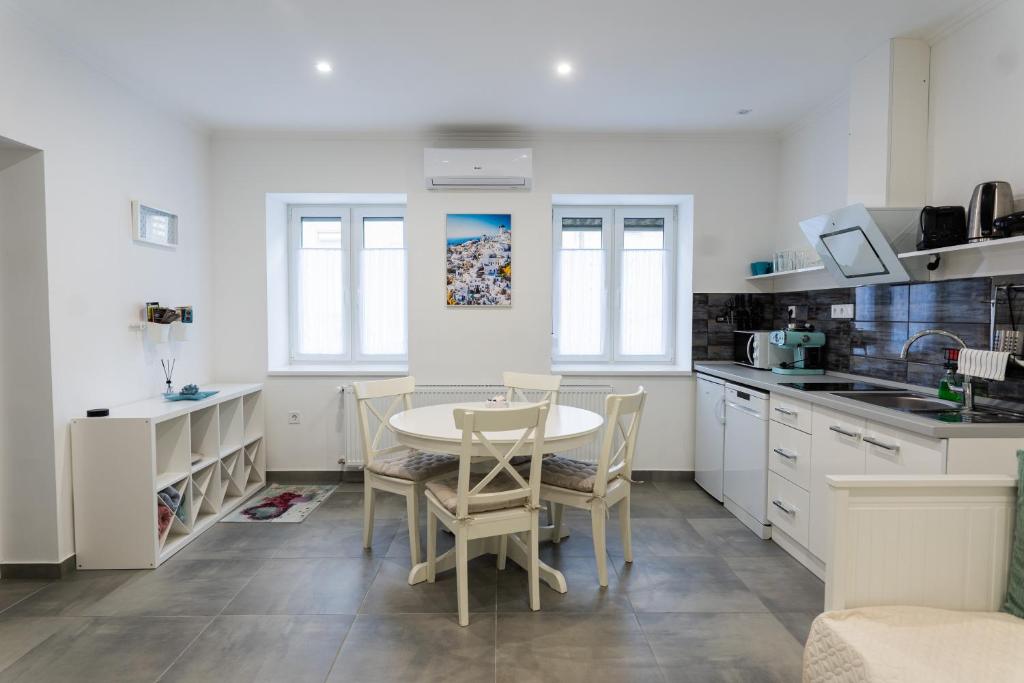 a kitchen with white cabinets and a table and chairs at MYKONOS APARTMAN in Makó