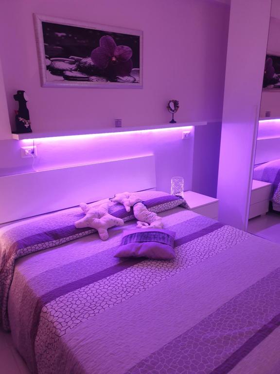 a purple bedroom with a bed with stuffed animals on it at Le case di Grazia in Gaeta