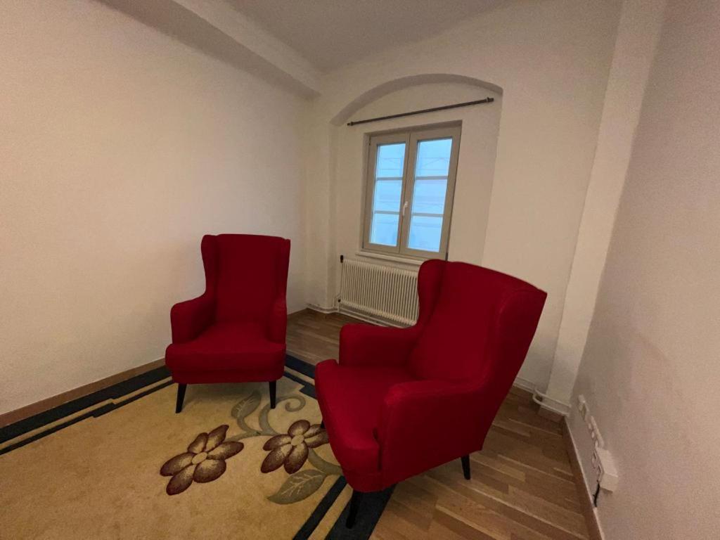 two red chairs in a room with a window at Hagmann&#39;s Altstadt Appartement in Krems an der Donau