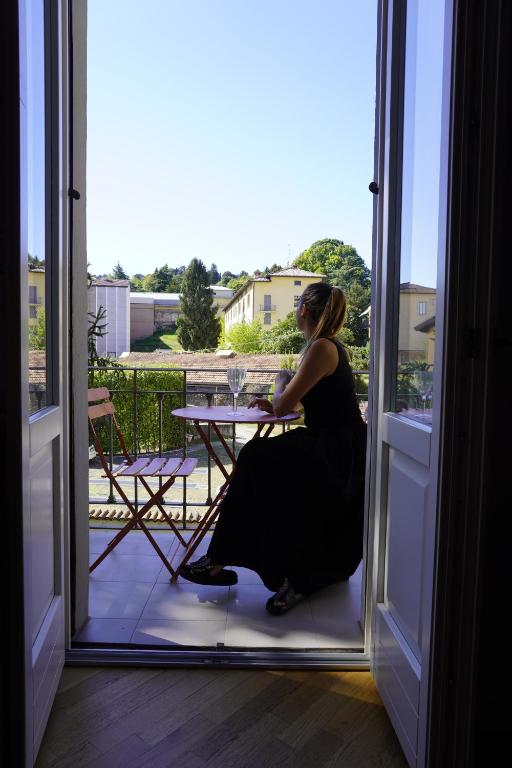 a woman sitting at a table on a balcony at Casa Gregis - Museums Area - 10 min walk to Upper town in Bergamo