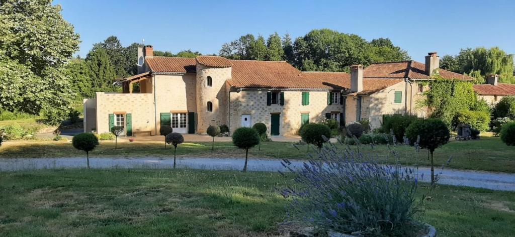 une grande maison en pierre avec des arbres devant elle dans l'établissement Domaine de la Basse Bobinière - Gîte et Chambres d'hôtes, à Thouarsais-Bouildroux