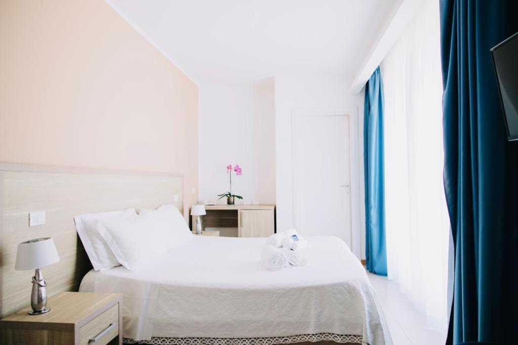a white bedroom with a white bed and a window at Hotel Villa Sveva in Cagliari