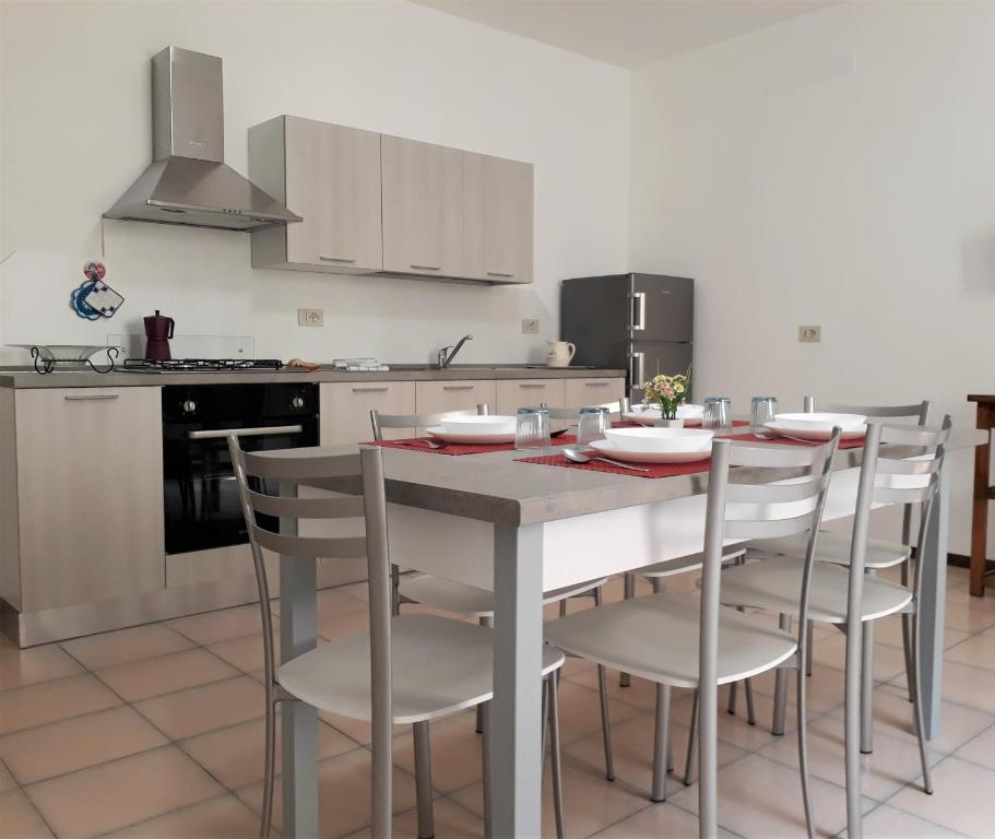 マローネにあるappartamento triesteのキッチン(テーブル、白い椅子付)、キッチン(コンロ付)