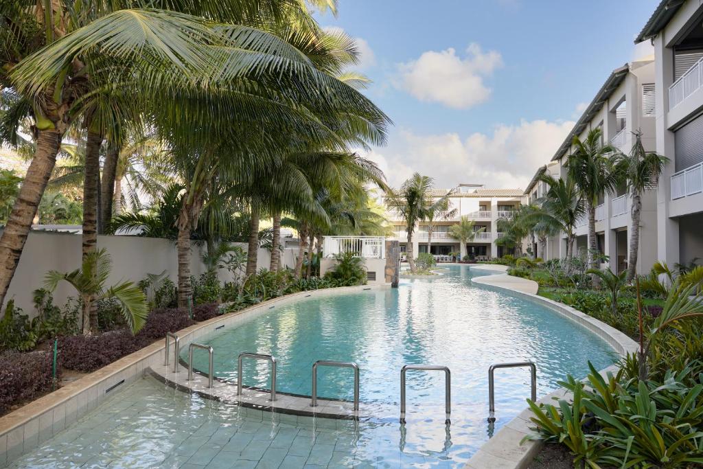 a swimming pool in a resort with palm trees at Ki Residences Apartments & Penthouse by LOV Mauritius, Pereybere in Pereybere