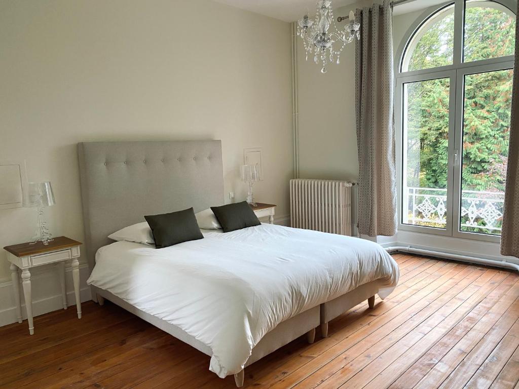 um quarto com uma grande cama branca e uma grande janela em Domaine de Bonneuil em Bonneuil-les-Eaux