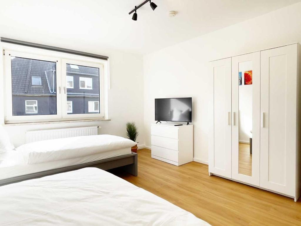 a white bedroom with two beds and a television at Cosy & Central-Apartments in Gelsenkirchen in Gelsenkirchen
