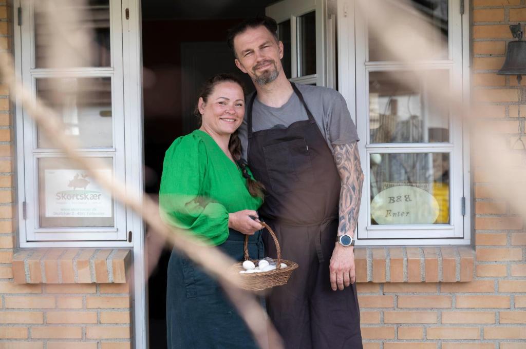 mężczyzna i kobieta stojący przed drzwiami w obiekcie Skortskær Bondegårdsferie w mieście Havnsø