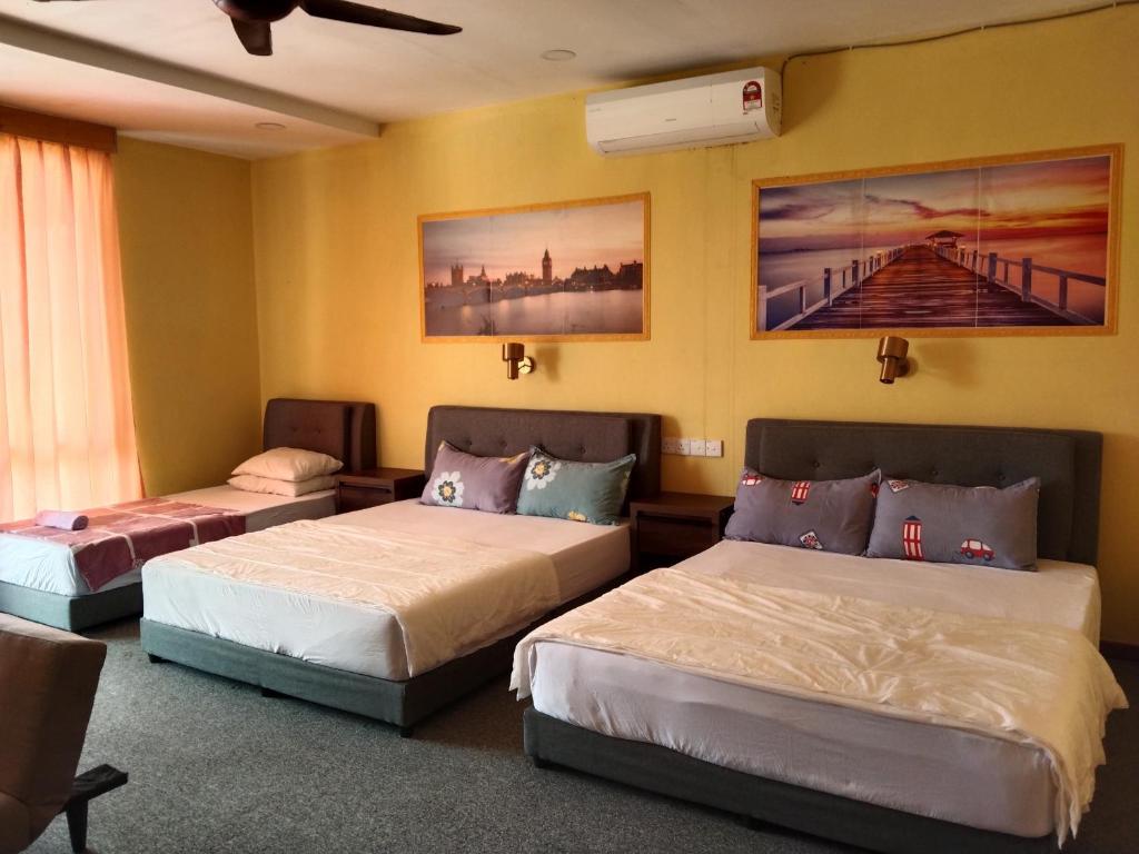 2 camas en una habitación con paredes amarillas en Putat Gajah Villa PASIR MAS en Pasir Mas