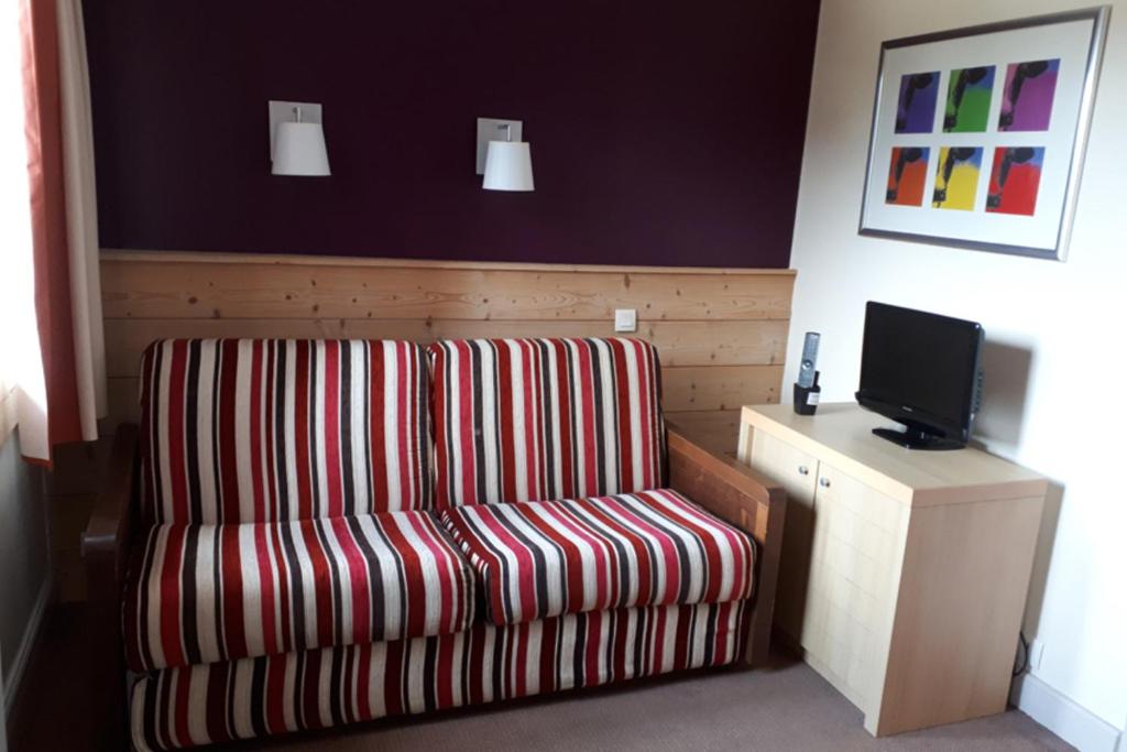 une chaise rayée rouge et blanche dans une chambre avec télévision dans l'établissement Nice Studio With Mountain View, à La Plagne Tarentaise