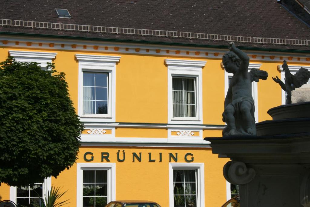 a yellow building with a statue in front of it at Gasthof Grünling in Wallsee