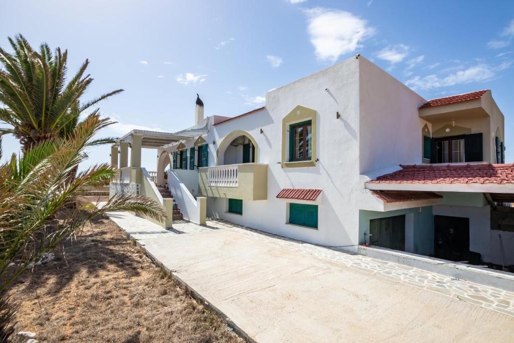 a house on the beach with a palm tree at Oceanviewvilla in Karpathos