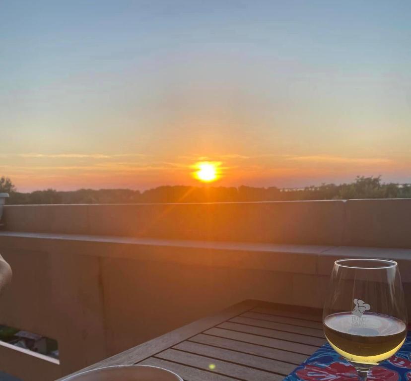 un bicchiere di vino seduto su un tavolo con il tramonto di Sisters'House a Lido
