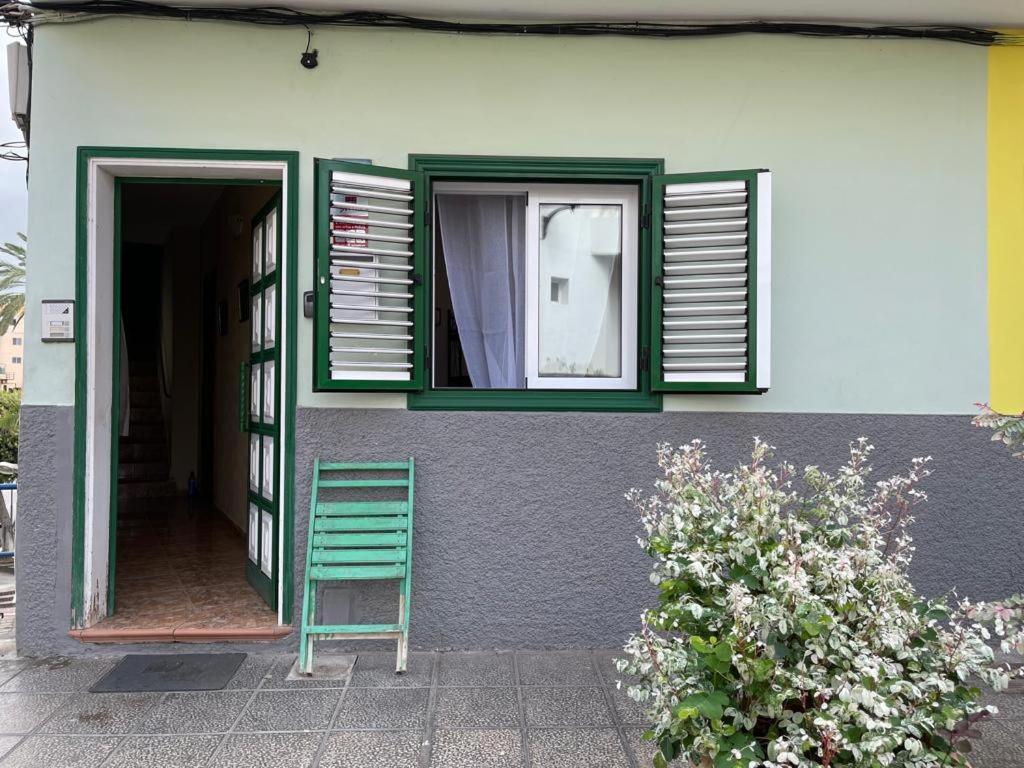 una sedia verde seduta fuori da una casa con finestra di Casa Tortuga 1era linea de playa a Alcalá