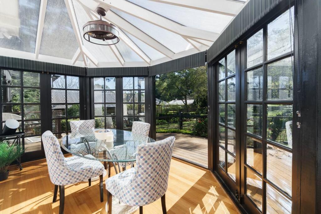 a conservatory with a glass table and chairs at Bryn-y-Mor Cottage Romantic Fireplace Couples in Leura