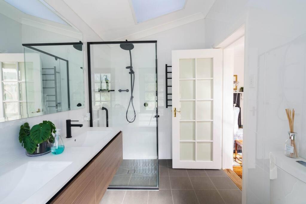a white bathroom with a shower and a sink at Bryn-y-Mor Cottage Romantic Fireplace Couples in Leura