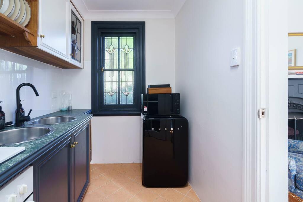 a black refrigerator in a kitchen with a window at Bryn-y-Mor Cottage Romantic Fireplace Couples in Leura