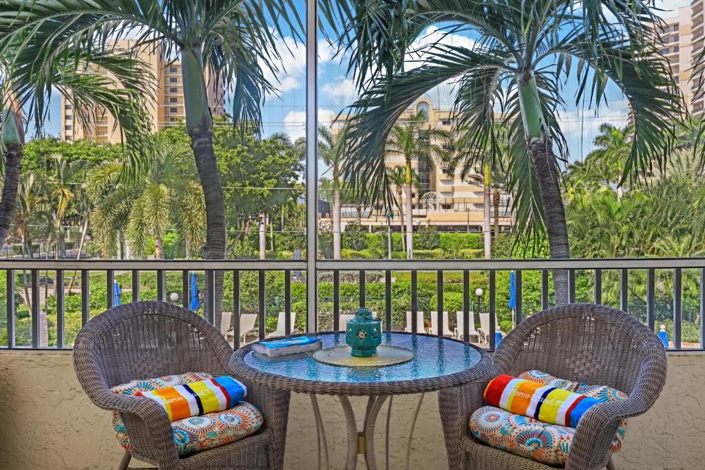 une table et deux chaises sur un balcon avec des palmiers dans l'établissement Idyllic inland condo with pool and beach access, à Marco Island